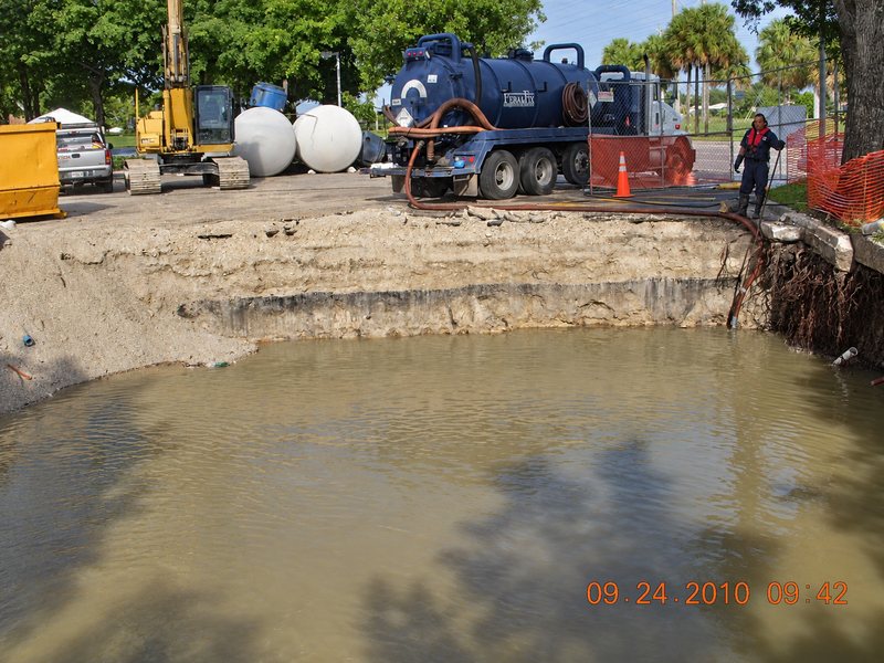 Water-filled excavation with equipment behind
