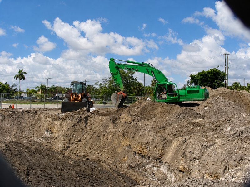 Excavator removing contaminated soil at a former fuel site