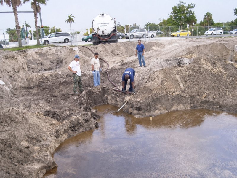 Field crew working beside a water-filled excavation